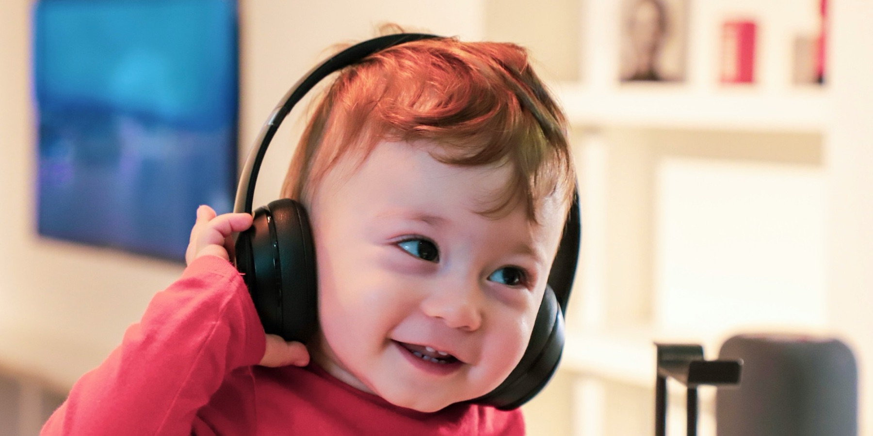 A smiling toddler wearing big black headphones