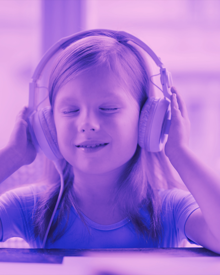 A child smiling with eyes closed while listening to a podcast on headphones